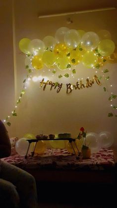 a birthday party with balloons and streamers hanging from the ceiling, along with a sign that says happy birthday