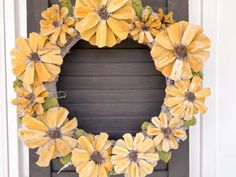 a wreath with yellow flowers hanging on the front door