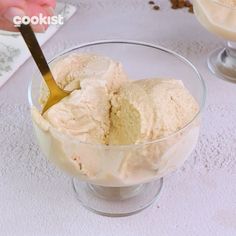 a bowl filled with ice cream on top of a white table next to a spoon