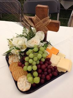 a tray with grapes, cheese and crackers on top of a white table cloth