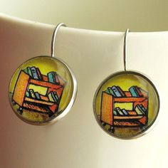 a pair of earrings with an image of a desk and bookshelf on it