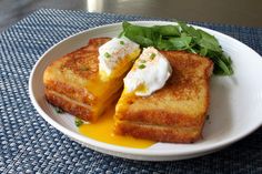 two grilled cheese sandwiches on a white plate with green leafy garnish