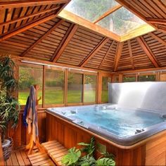 a hot tub inside of a wooden structure with plants in the corner next to it