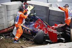 two men working on a race car that has crashed into the side of a building