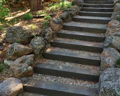 a set of stone steps leading up to the top of a hill with rocks on each side