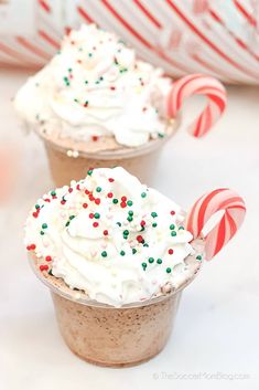 two cups filled with whipped cream and candy canes