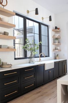 a kitchen with black cabinets and white counter tops, gold pulls on the doors and shelves