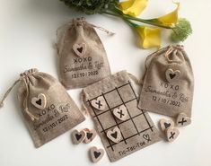 four personalized wedding favors in burlap bags with cross and hearts on them