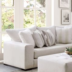 a living room with white furniture and pictures on the wall above it's windows