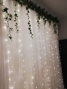 the curtains are covered with white lights and ivy vines hanging from it's sides