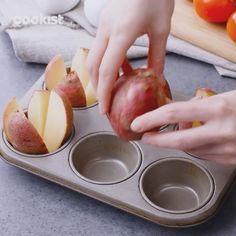 someone is peeling an apple into some muffin tins