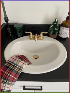 a white sink sitting on top of a black counter next to a bottle of wine