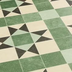 a green and white tiled floor with black triangles