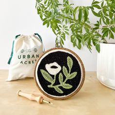 a plant is sitting next to a bag on a table with a wooden spoon and brush