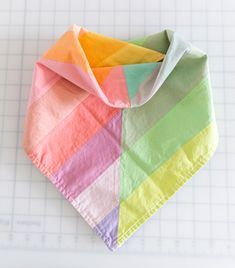 the folded napkins have different colors of paper on top of each other, including pink, yellow, green, and blue