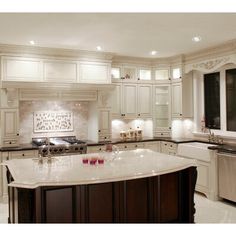 a large kitchen with white cabinets and marble counter tops, along with a center island