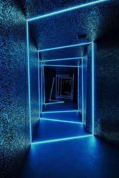 an empty room with blue light coming from the ceiling and walls, all lit up by neon lights