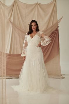 a woman in a wedding dress posing for the camera with her arms out and hands on her hips