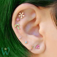 a close up of a person's ear with different colored stones on it and flowers in the middle