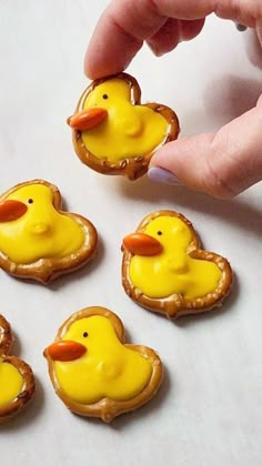 a person is holding some cookies with yellow icing on them and there are little rubber ducks in the middle