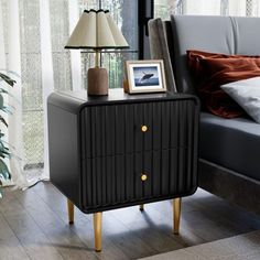 a black cabinet sitting on top of a wooden floor next to a bed and lamp