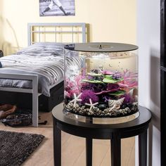 an aquarium is on top of a table in front of a bed