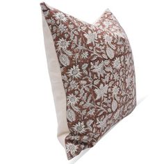 a brown and white pillow with floral print on the front, sitting against a white background