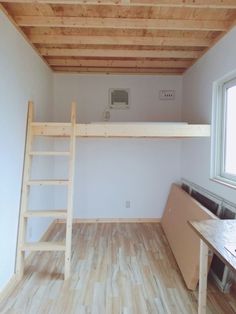 a loft bed with a ladder in the middle of it next to a desk and window