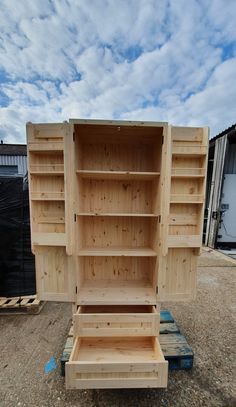 a wooden bookcase sitting on top of a pallet in the middle of a dirt field