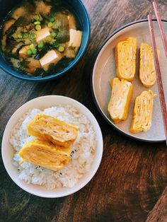 two bowls of food on a table with chopsticks next to one bowl of rice