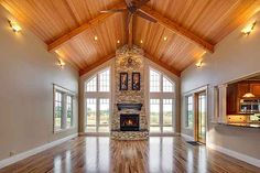 an empty living room with wood floors and vaulted ceiling