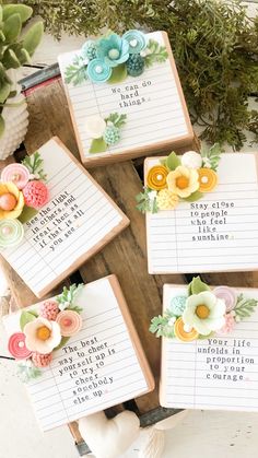 four handmade notepads with flowers on them sitting on top of a wooden table