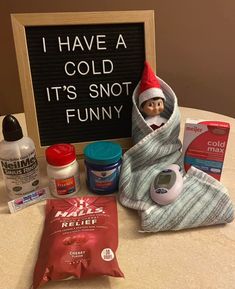 an elf's christmas gift set up on a table next to a sign that says i have a cold it's not funny