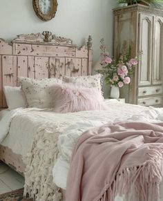 a bed with pink pillows and blankets on top of it in a bedroom next to a dresser