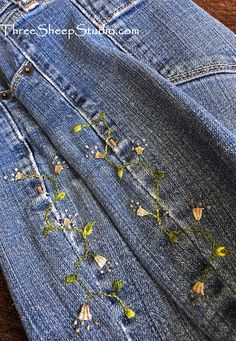 an old pair of jeans with some flowers on the inside of it and holes in the back