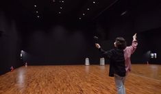 a man standing on top of a wooden floor in front of a projector screen