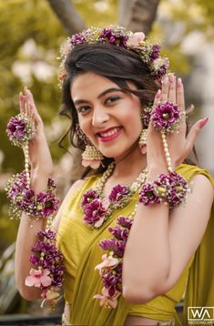 a woman with flowers in her hair and bracelets around her neck posing for the camera