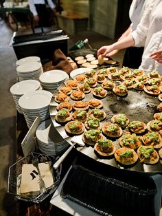 a woman standing in front of a table filled with pies and cupcakes