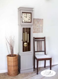 a grandfather clock sitting on top of a cabinet next to a chair