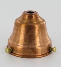 an antique brass bell with two green knobs on the top and bottom, sitting against a white background