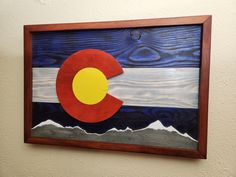 a wooden sign with the flag of colorado painted on it