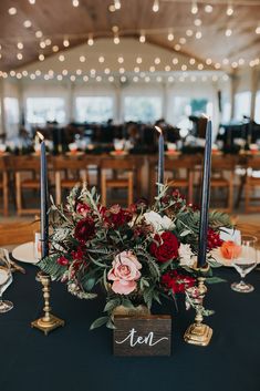 a centerpiece with flowers and candles on a black table cloth at a wedding reception