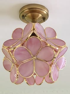 a pink flower shaped light fixture hanging from a ceiling