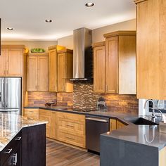 a large kitchen with wooden cabinets and stainless steel appliances, including an island in the middle