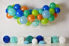 balloons and tissue pom poms are hanging from the wall