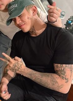 two men sitting next to each other with tattoos on their arms