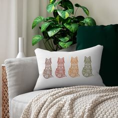 a white couch sitting next to a potted plant and a pillow on top of it