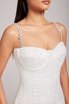 a woman wearing a white dress with beading on it