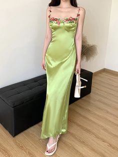 a woman in a green dress standing next to a couch