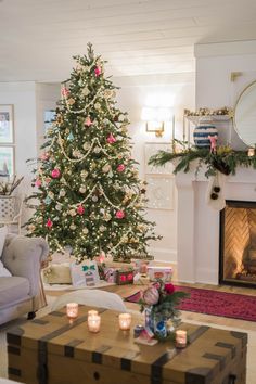 a living room with a christmas tree in the corner and candles on the coffee table